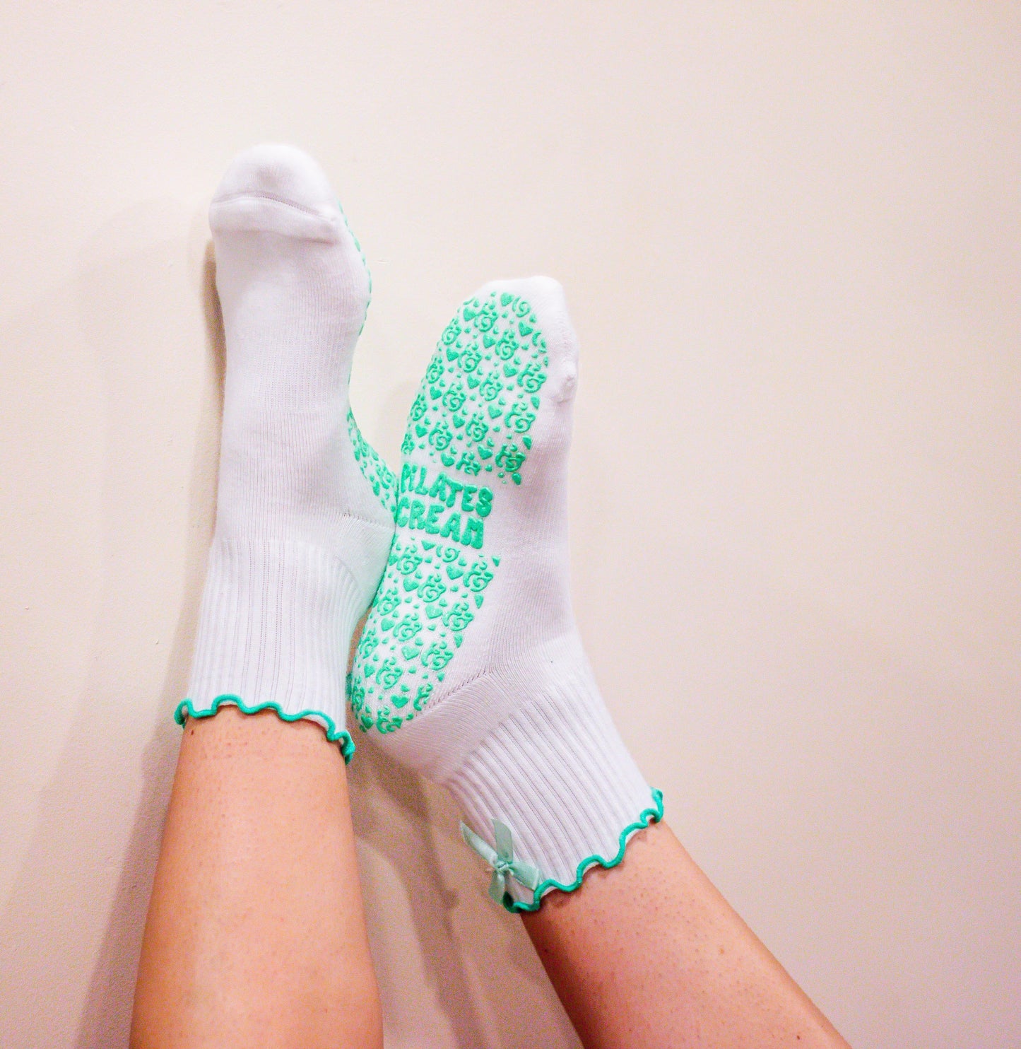 White socks with mint green textured sole and frill trim , with back mint bow on a white background