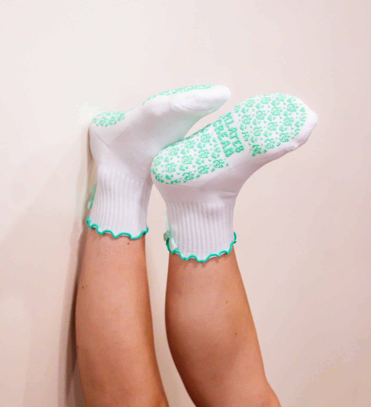 White socks with mint green frill, mint green bow and extra grip patterns on a plain background