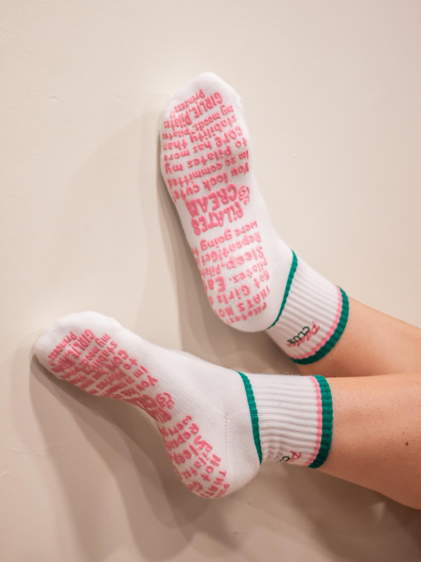 White socks with pink text and green trim on a beige background